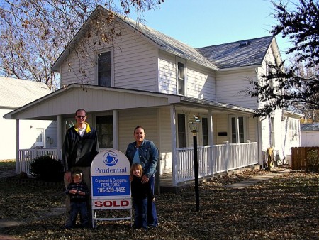 first time home buyers in front of sold house