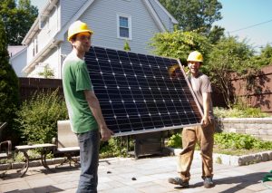 solar installers carrying a solar panel - are solar panels worth it