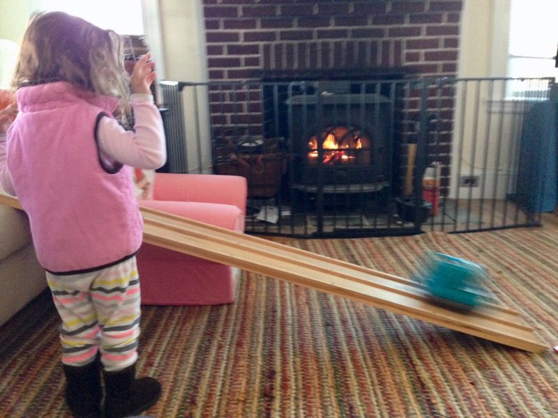 child playing in front of wood stove with fire safety gate - wood stove vs. fireplace