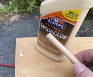 holding a 3/8 dowel next to a bottle of elmers wood glue
