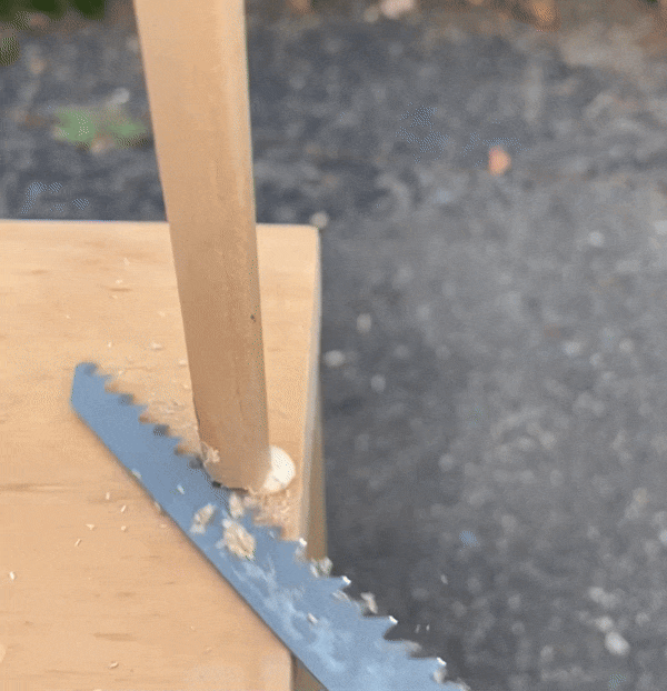 using a handsaw to cut a wood dowel flush with the board
