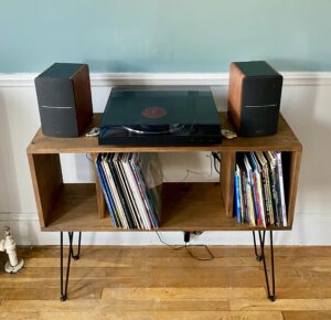 diy midcentury modern record player stand, with turntable and speakers on top and albums in the storage cubbies